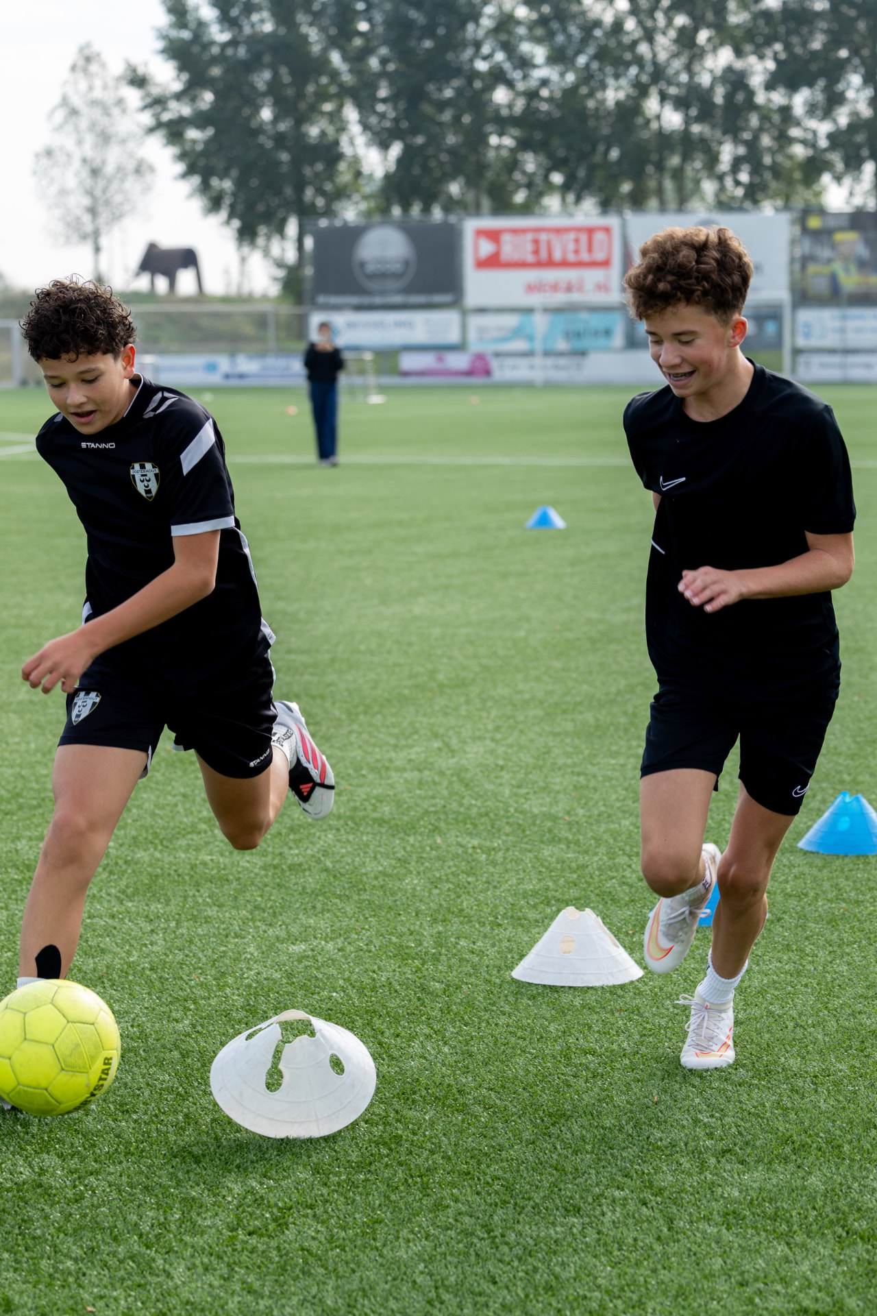 Training bij De Oosterhoutse Voetbalschool: kinderen dribbelen met de bal tussen pionnen