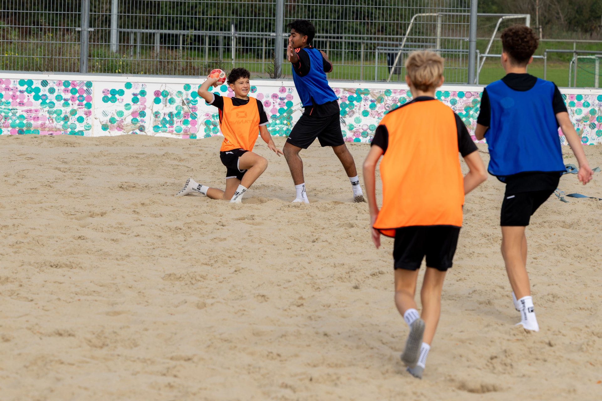 Kinderen spelen een handbalpartij op het zandveld